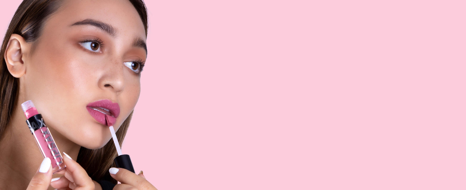 A model applying LIPSAX in the shade selfie to her lips on a light pink background